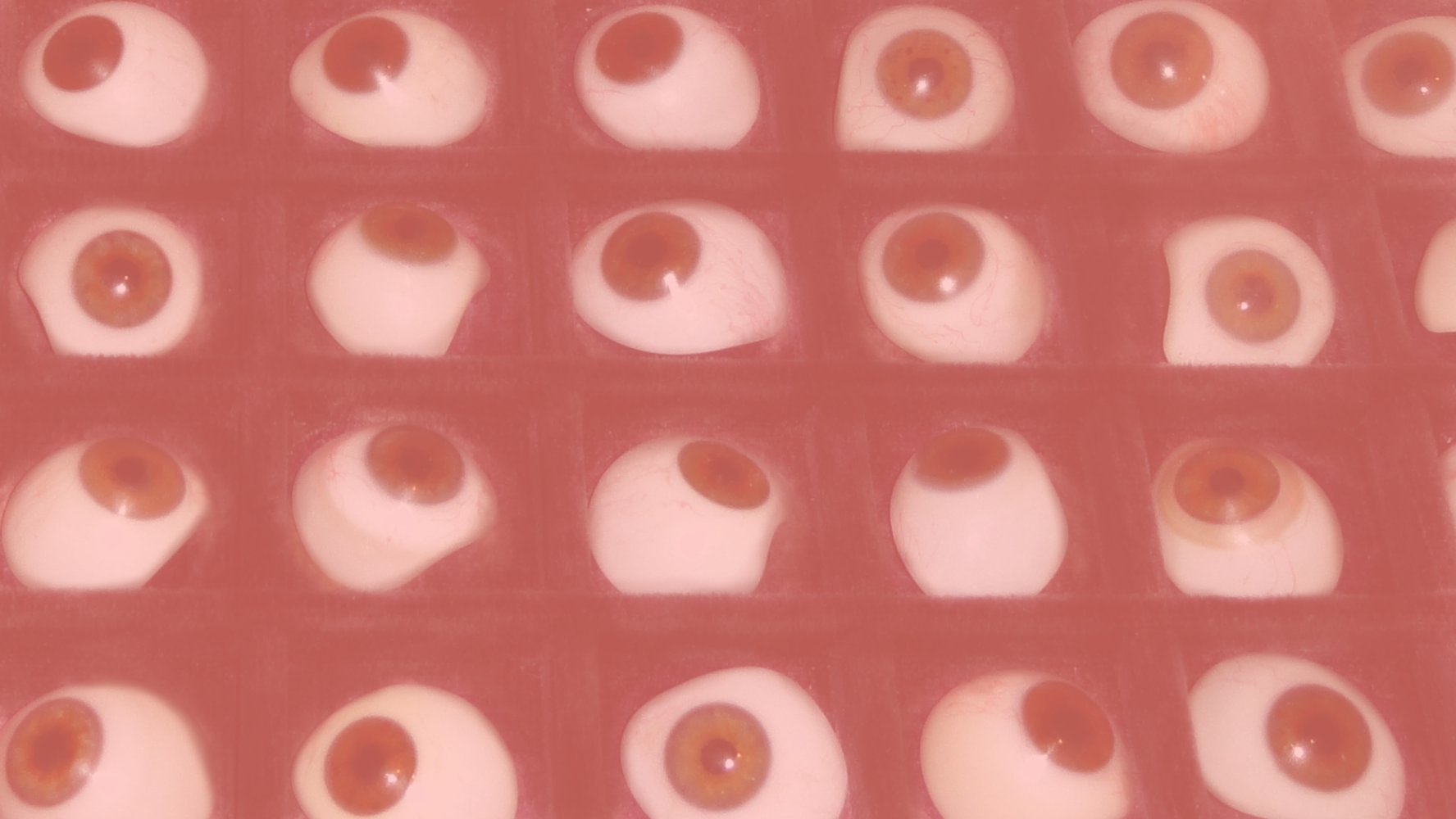 Array of glass eyes with a semi-transparent salmon-coloured overlay.